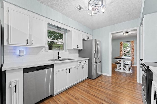2014 17th St N, Texas City, TX 77590 - kitchen featuring stainless steel appliances, a textured ceiling, backsplash, light countertops, and light wood-style floors