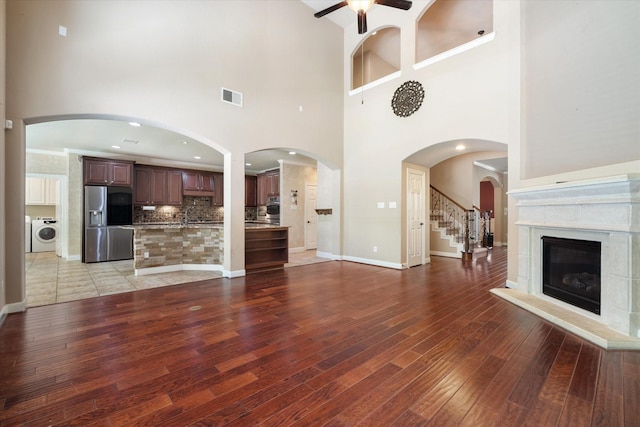 15602 Shining Brook Ct, Houston, TX 77044 - unfurnished living room with washer / dryer, ceiling fan, light wood finished floors, a high ceiling, and a high end fireplace