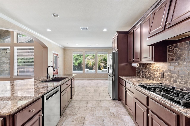 15602 Shining Brook Ct, Houston, TX 77044 - kitchen featuring appliances with stainless steel finishes, decorative backsplash, arched walkways, light stone counters, and ornamental molding
