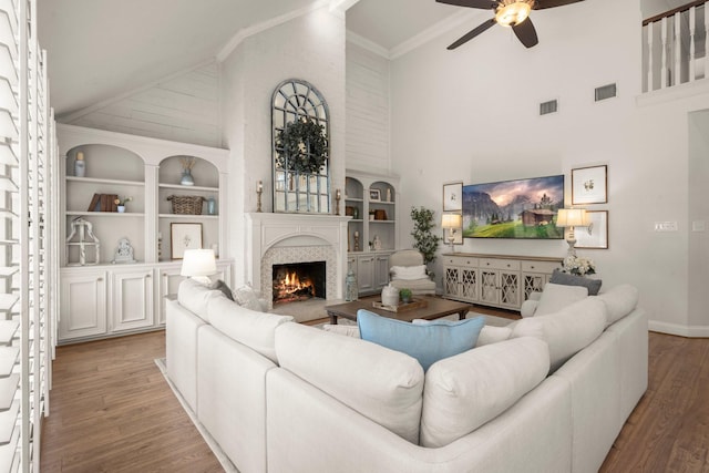 13306 Golden Valley Dr, Cypress, TX 77429 - living room featuring high vaulted ceiling, a ceiling fan, wood finished floors, a warm lit fireplace, and built in features