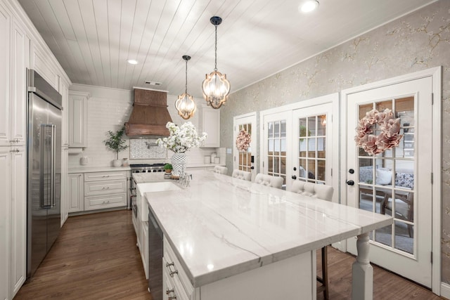 13306 Golden Valley Dr, Cypress, TX 77429 - kitchen featuring stainless steel built in fridge, custom range hood, french doors, a chandelier, and white cabinetry