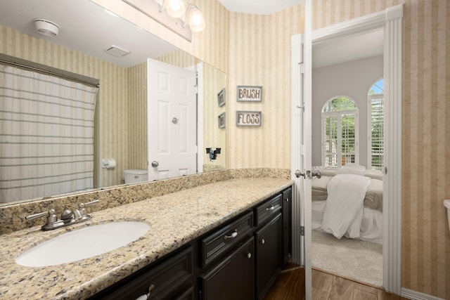 13306 Golden Valley Dr, Cypress, TX 77429 - bathroom featuring wallpapered walls, wood finished floors, connected bathroom, vanity, and a shower with curtain