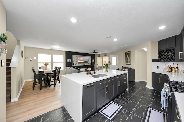 19110 Remington Springs Dr, Houston, TX 77073 - kitchen with stainless steel gas stove, open floor plan, dark marble finish floors, a kitchen island with sink, and light countertops