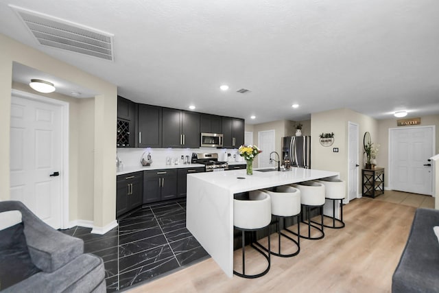 19110 Remington Springs Dr, Houston, TX 77073 - kitchen with stainless steel appliances, light countertops, a breakfast bar area, an island with sink, and open floor plan