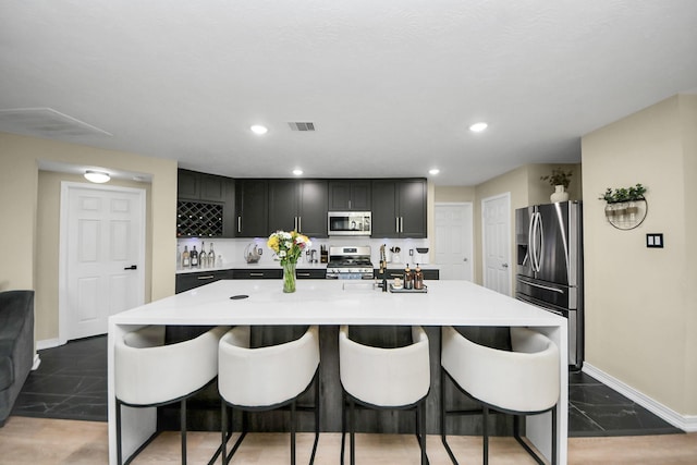 19110 Remington Springs Dr, Houston, TX 77073 - kitchen with stainless steel appliances, a breakfast bar, light countertops, a kitchen island with sink, and recessed lighting