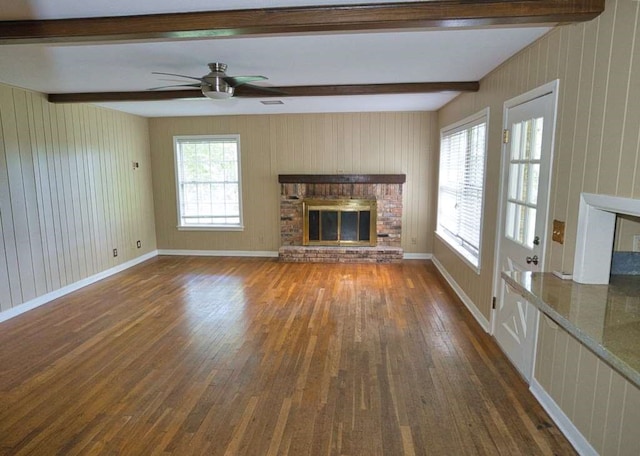 524 Oak Dr, Lake Jackson, TX 77566 - unfurnished living room with a fireplace, dark wood finished floors, beam ceiling, ceiling fan, and wood walls