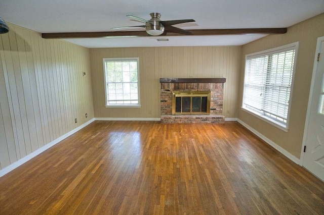 524 Oak Dr, Lake Jackson, TX 77566 - unfurnished living room with beam ceiling, wood finished floors, a ceiling fan, wooden walls, and a fireplace