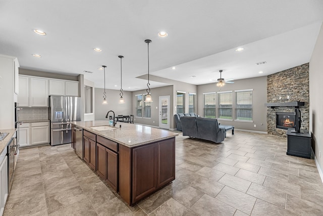 30212 Green Meadows Ln, Brookshire, TX 77423 - kitchen featuring stainless steel appliances, open floor plan, a stone fireplace, decorative backsplash, and recessed lighting