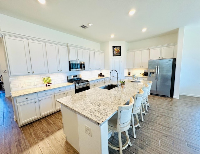 11119 Alpenhorn Pl, Tomball, TX 77375 - kitchen with stainless steel appliances, wood finish floors, white cabinetry, an island with sink, and recessed lighting