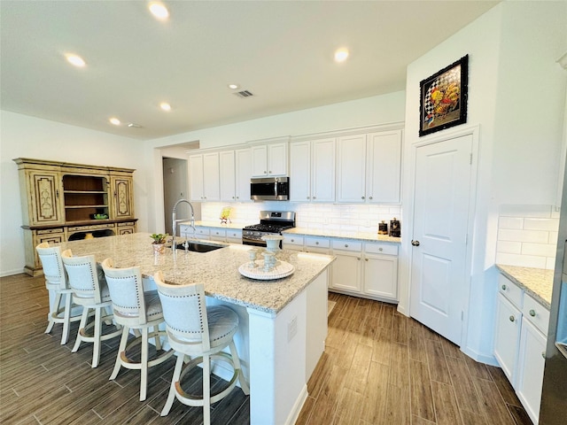 11119 Alpenhorn Pl, Tomball, TX 77375 - kitchen featuring appliances with stainless steel finishes, a kitchen island with sink, white cabinets, decorative backsplash, and recessed lighting