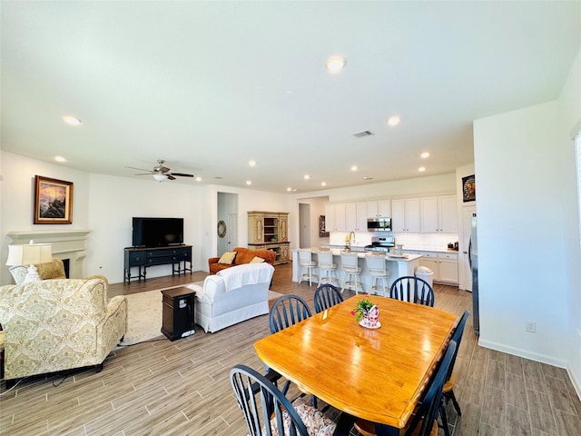 11119 Alpenhorn Pl, Tomball, TX 77375 - dining room featuring recessed lighting, light wood finished floors, a ceiling fan, and a fireplace