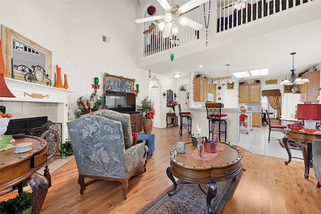 16535 Mccormick Dr, Houston, TX 77095 - living area with a ceiling fan, light wood finished floors, a fireplace, a high ceiling, and a chandelier