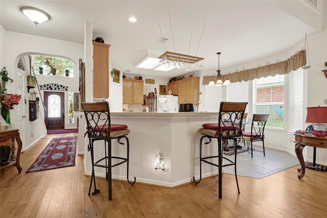 16535 Mccormick Dr, Houston, TX 77095 - kitchen with freestanding refrigerator, a kitchen breakfast bar, light wood-style floors, a chandelier, and recessed lighting