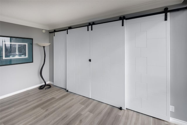 5001 Woodway Dr Unit 1704, Houston, TX 77056 - unfurnished bedroom with a barn door, ornamental molding, and light wood-style floors