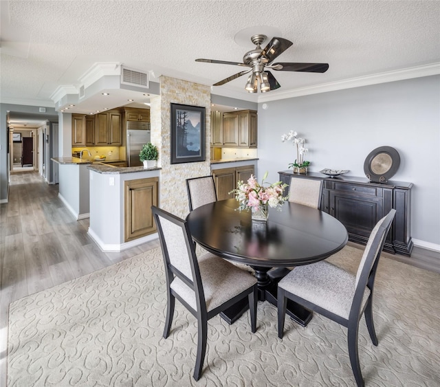 5001 Woodway Dr Unit 1704, Houston, TX 77056 - dining area featuring ornamental molding, light wood-style flooring, a textured ceiling, and a ceiling fan