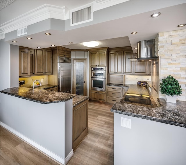 5001 Woodway Dr Unit 1704, Houston, TX 77056 - kitchen with stainless steel appliances, island range hood, light wood-style flooring, a peninsula, and recessed lighting