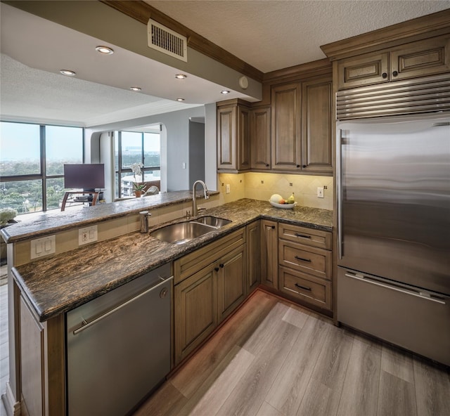 5001 Woodway Dr Unit 1704, Houston, TX 77056 - kitchen featuring appliances with stainless steel finishes, a peninsula, light wood-style floors, dark stone countertops, and recessed lighting