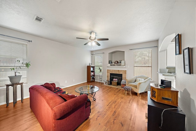 14711 Trailbrook Dr, Houston, TX 77095 - living room with light wood finished floors, ceiling fan, a tile fireplace, and a textured ceiling