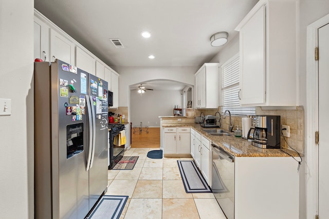 14711 Trailbrook Dr, Houston, TX 77095 - kitchen with appliances with stainless steel finishes, decorative backsplash, white cabinetry, ceiling fan, and arched walkways