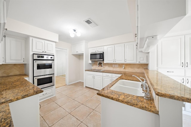 14708 Perthshire Rd Unit F, Houston, TX 77079 - kitchen with stainless steel appliances, a peninsula, backsplash, white cabinetry, and stone counters