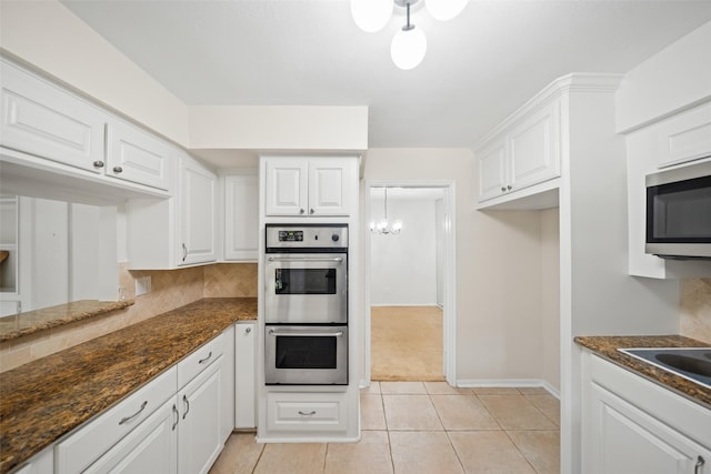 14708 Perthshire Rd Unit F, Houston, TX 77079 - kitchen with stainless steel appliances, white cabinetry, backsplash, light tile patterned flooring, and dark stone counters