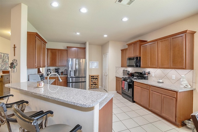 1911 Vineyard Bend Ct, Pearland, TX 77581 - kitchen featuring black appliances, a breakfast bar, tasteful backsplash, recessed lighting, and light tile patterned floors