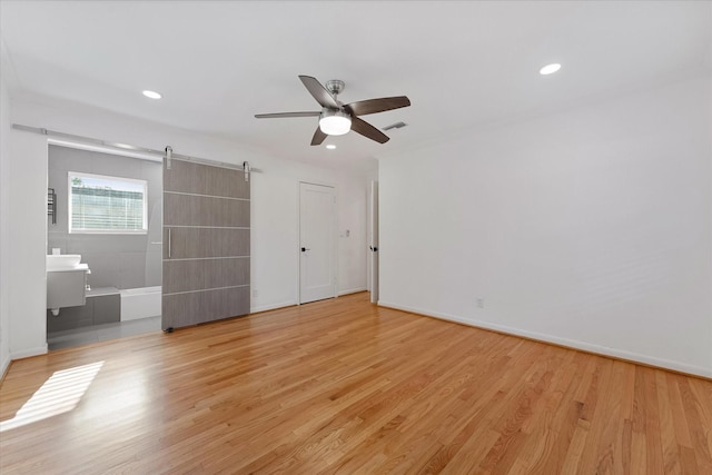 7807 Ella Lee Ln, Houston, TX 77063 - unfurnished bedroom with light wood-style floors, recessed lighting, a barn door, connected bathroom, and ceiling fan