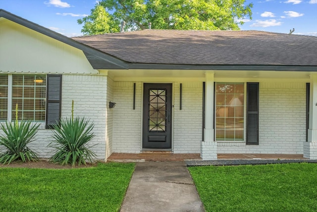 7807 Ella Lee Ln, Houston, TX 77063 - entrance to property with roof with shingles, brick siding, a porch, and a lawn