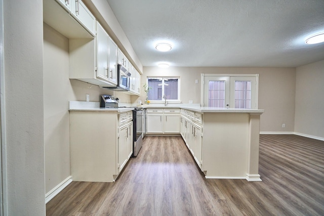 10818 Briar Forest Dr Unit 34, Houston, TX 77042 - kitchen with stainless steel appliances, a peninsula, wood finished floors, light countertops, and a textured ceiling