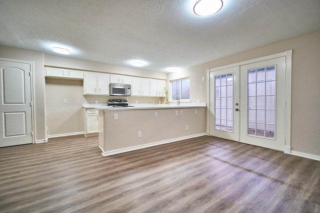 10818 Briar Forest Dr Unit 34, Houston, TX 77042 - kitchen featuring appliances with stainless steel finishes, french doors, white cabinetry, a peninsula, and wood finished floors