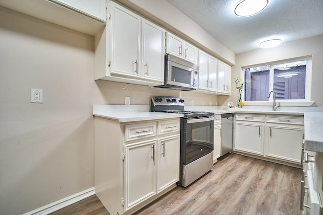 10818 Briar Forest Dr Unit 34, Houston, TX 77042 - kitchen featuring stainless steel appliances, light wood-style floors, white cabinetry, and light countertops