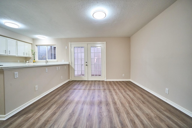 10818 Briar Forest Dr Unit 34, Houston, TX 77042 - kitchen featuring french doors, wood finished floors, a textured ceiling, light countertops, and white cabinetry