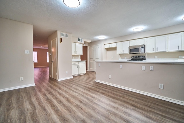 10818 Briar Forest Dr Unit 34, Houston, TX 77042 - kitchen featuring appliances with stainless steel finishes, wood finished floors, white cabinets, light countertops, and a textured ceiling