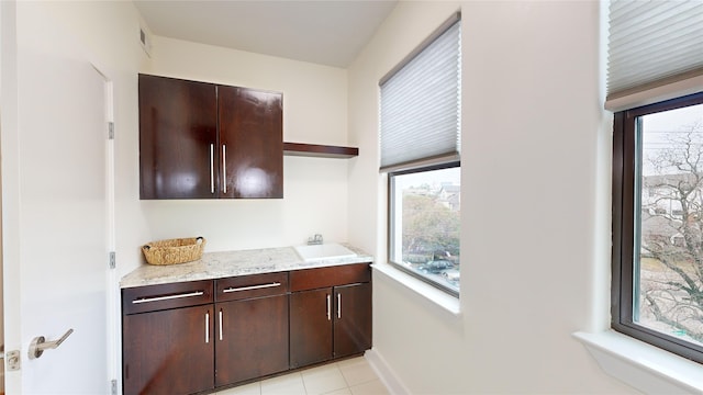 1767 Michigan St, Houston, TX 77006 - kitchen with open shelves, dark brown cabinets, light stone counters, and light tile patterned floors