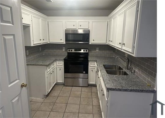 3629 Lydia St Unit A, Houston, TX 77021 - kitchen with appliances with stainless steel finishes, light tile patterned flooring, tasteful backsplash, and white cabinetry
