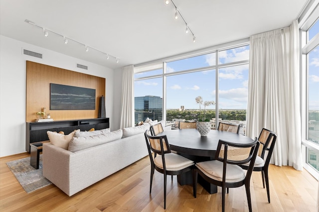 2207 Bancroft St Unit 1104, Houston, TX 77027 - dining space with rail lighting, light wood finished floors, and a wall of windows