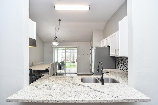 16810 Rockstone, Houston, TX 77084 - kitchen with freestanding refrigerator, white cabinets, light stone counters, hanging light fixtures, and tasteful backsplash