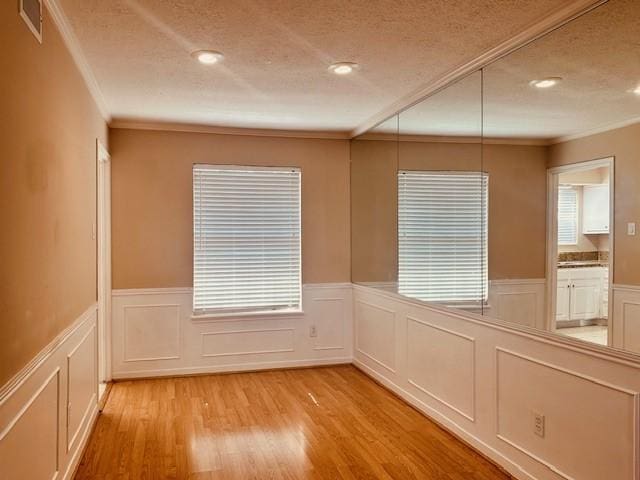 7900 Westheimer Rd Unit 143, Houston, TX 77063 - spare room featuring crown molding, a textured ceiling, light wood finished floors, wainscoting, and recessed lighting
