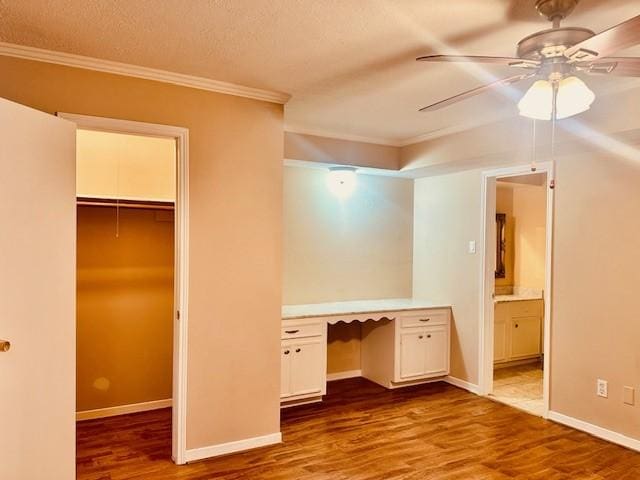 7900 Westheimer Rd Unit 143, Houston, TX 77063 - unfurnished bedroom with ornamental molding, a walk in closet, wood finished floors, built in desk, and a closet