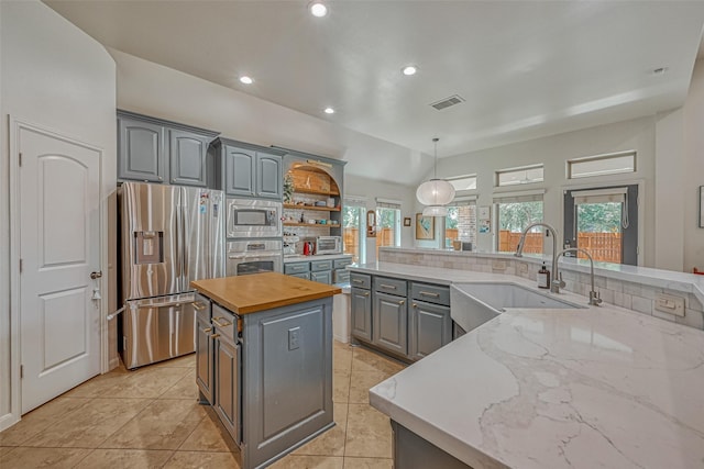 5918 Emmit Creek Ln, Sugar Land, TX 77479 - kitchen featuring stainless steel appliances, gray cabinetry, a center island, recessed lighting, and light tile patterned flooring
