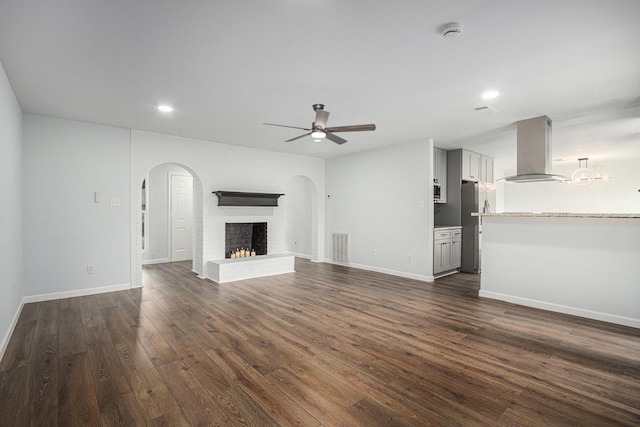 8419 Sterlingshire St, Houston, TX 77078 - unfurnished living room featuring ceiling fan, dark wood-style flooring, arched walkways, a fireplace, and recessed lighting