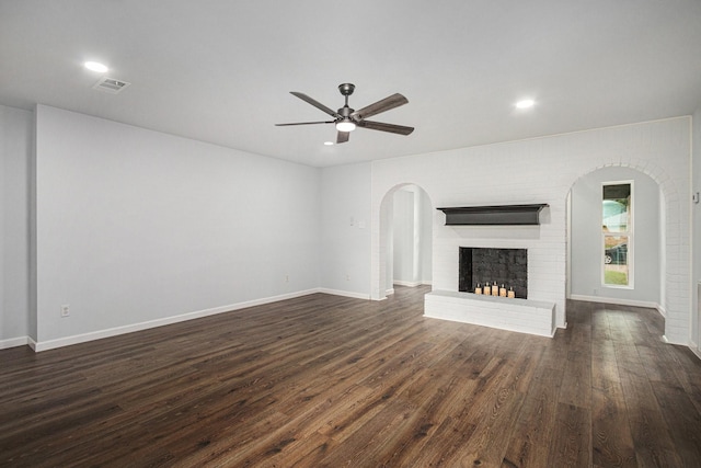 8419 Sterlingshire St, Houston, TX 77078 - unfurnished living room featuring ceiling fan, dark wood-style floors, arched walkways, a brick fireplace, and recessed lighting