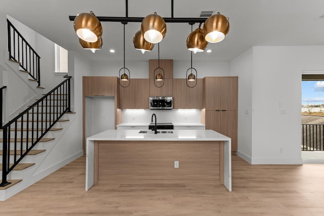 1803 Sakowitz St, Houston, TX 77020 - kitchen featuring stainless steel microwave, light wood-type flooring, light countertops, modern cabinets, and a kitchen island with sink