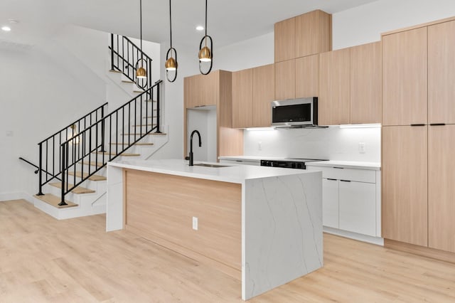 1803 Sakowitz St, Houston, TX 77020 - kitchen with modern cabinets, stainless steel microwave, light wood-style flooring, a center island with sink, and recessed lighting