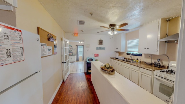 216 E Plantation Dr, Clute, TX 77531 - kitchen with white appliances, under cabinet range hood, a ceiling fan, dark wood-type flooring, and a textured ceiling