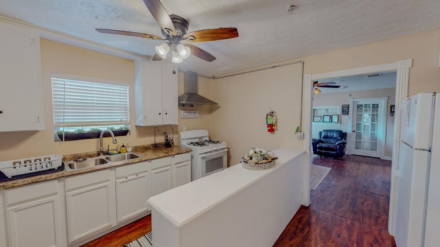 216 E Plantation Dr, Clute, TX 77531 - kitchen with wall chimney range hood, white appliances, a ceiling fan, dark wood finished floors, and white cabinetry