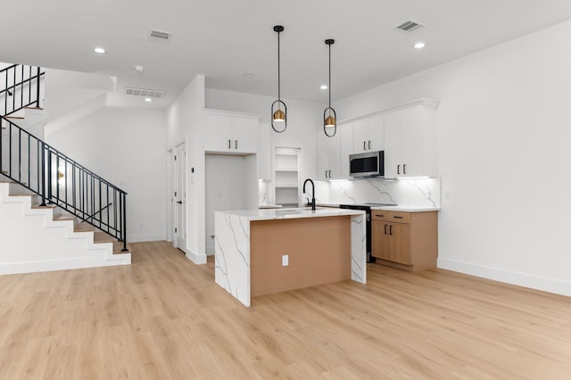 1805 Sakowitz St, Houston, TX 77020 - kitchen with appliances with stainless steel finishes, light wood-style flooring, a kitchen island with sink, recessed lighting, and hanging light fixtures