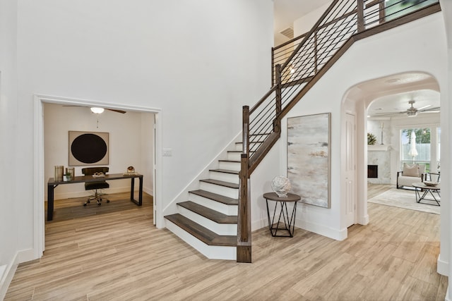 13826 Swan Hollow Ln, Houston, TX 77041 - stairs featuring ceiling fan, wood finished floors, a high ceiling, a fireplace, and arched walkways