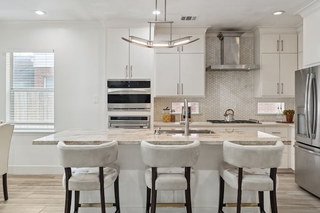 13826 Swan Hollow Ln, Houston, TX 77041 - kitchen featuring wall chimney exhaust hood, stainless steel appliances, crown molding, a kitchen breakfast bar, and plenty of natural light