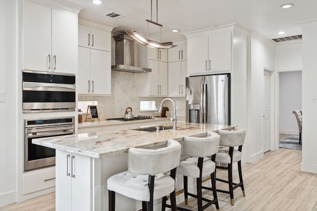 13826 Swan Hollow Ln, Houston, TX 77041 - kitchen with stainless steel appliances, wall chimney range hood, a kitchen island with sink, recessed lighting, and decorative backsplash